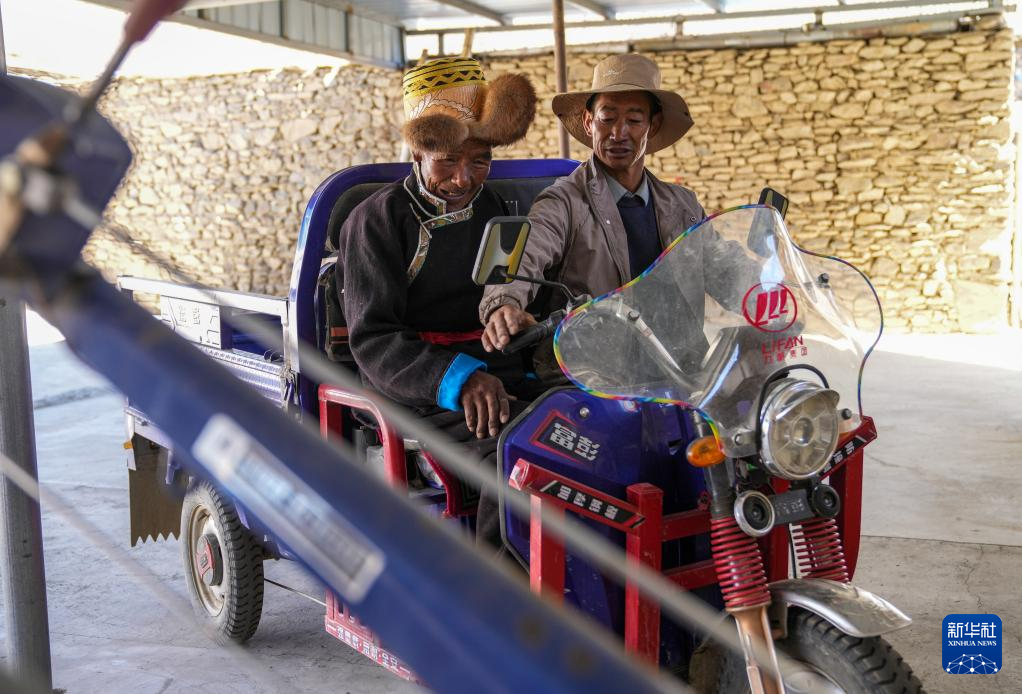 白玛扎西（左）坐在女婿新买的电动三轮摩托车上（3月26日摄）。