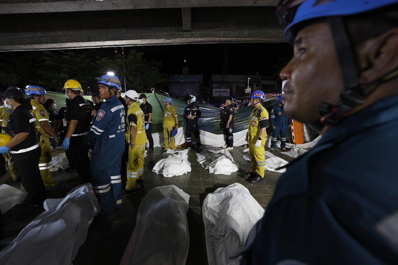 ▲当地时间2026年7月13日，泰国曼谷，救援人员在被烧毁的酒吧外搬运火灾遇难者遗体（图据视觉中国）