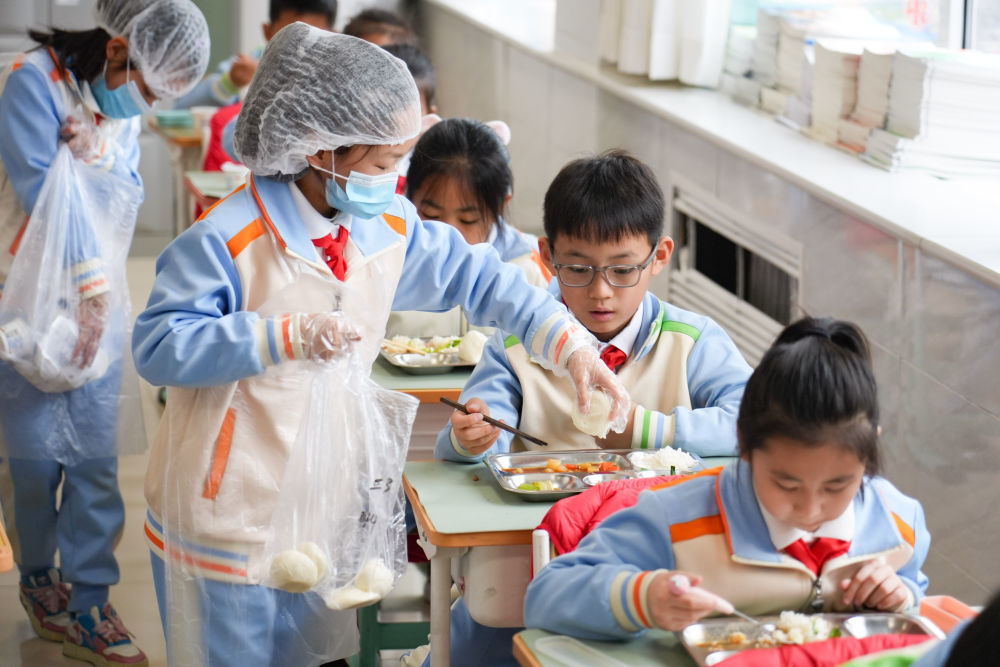 2026年3月2日,北京首都师范大学附属小学三年级3班分餐员在教室分馒头。新华社记者 谢晗 摄