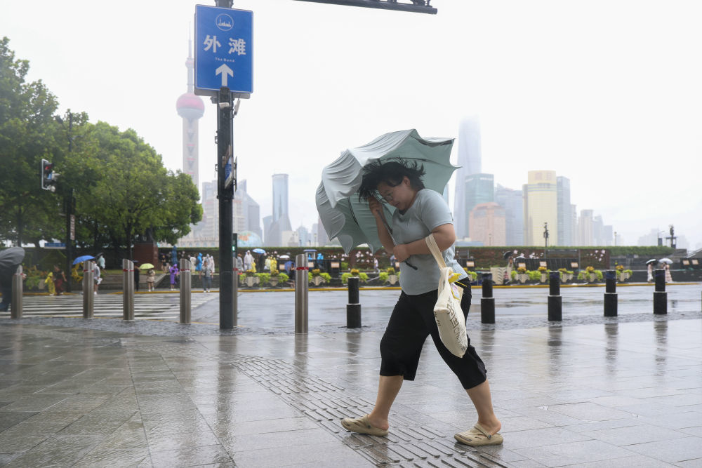 8月9日，在上海黄浦区南京东路上，人们冒雨前行。新华社记者 王翔 摄