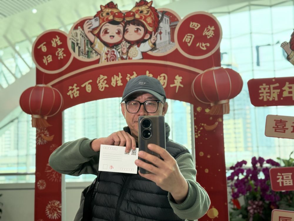 2月10日，在厦门站“话百家姓 过中国年”主题文化活动现场，台胞李高雄拿着专属姓氏明信片自拍留念。新华社记者 付敏 摄