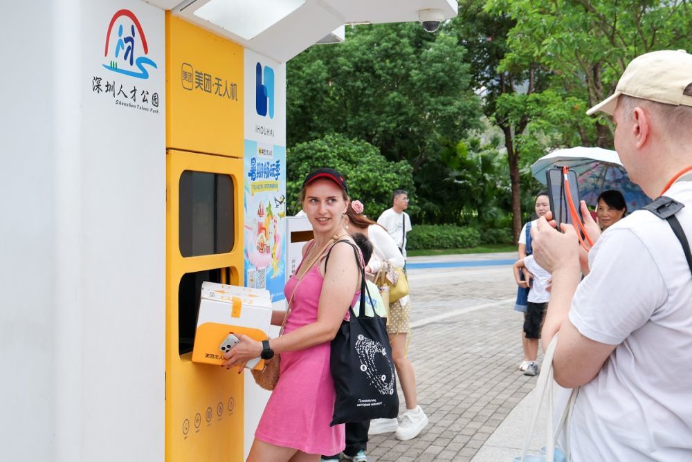 外国游客在深圳人才公园体验美团无人机送外卖(8月3日摄)。新华社记者 梁旭 摄