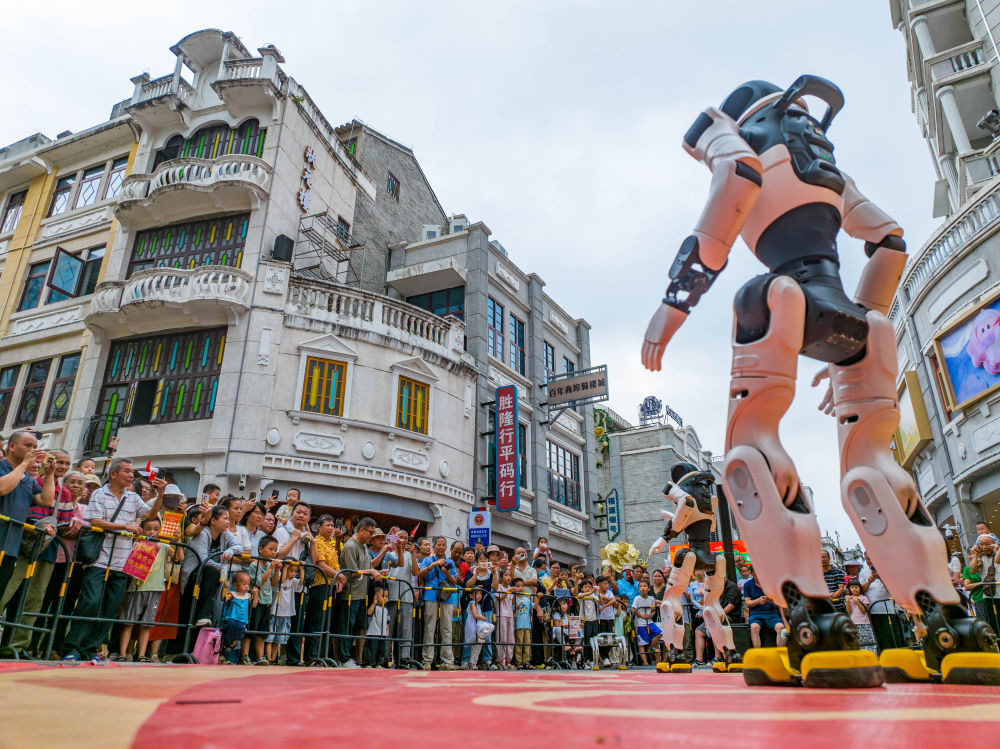 10月1日,在广西梧州骑楼城,机器人表演吸引游客驻足观看。新华社发(何华文 摄)