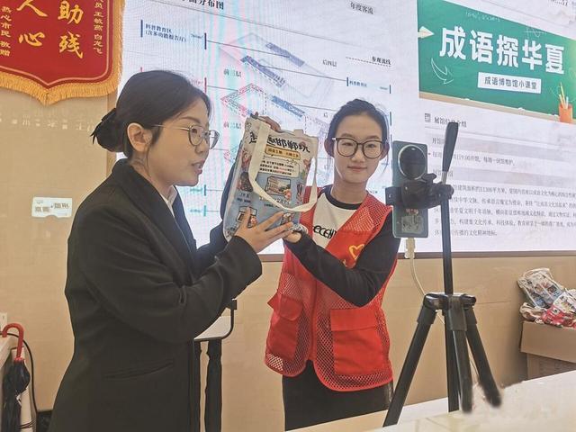 10月1日,在邯郸成语博物馆一楼服务台,志愿者陈祎鑫(右)协助工作人员进行文旅直播。 河北日报记者 陈正 摄