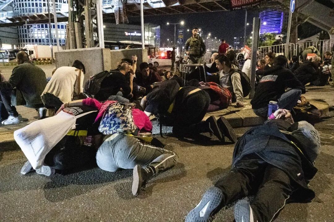 2023年,12月2日,在以色列城市特拉维夫,防空警报响起时,身处室外的人们降低身位避难/新华社记者 陈君清 摄