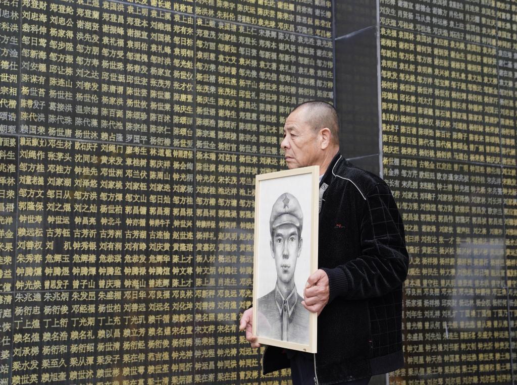 在瑞金革命烈士陵园，烈士家属手捧画像从烈士名单前走过（4月1日摄）。新华社记者 周密 摄