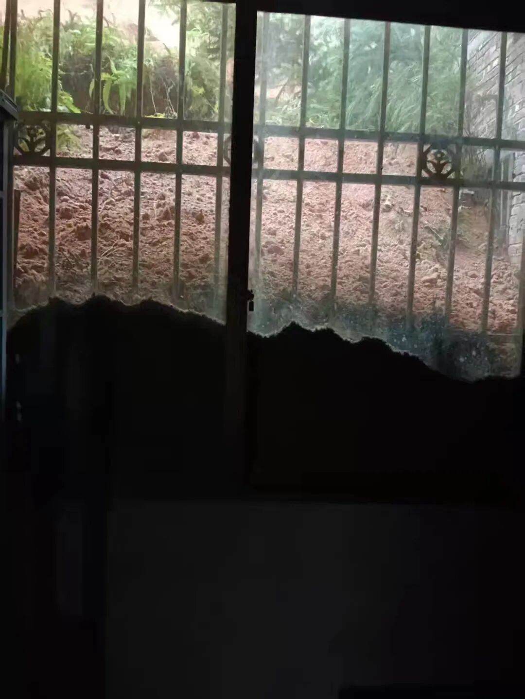 从屋内向外望去，滑坡堆积的泥土已漫过半个窗户的高度 / 受访者供图