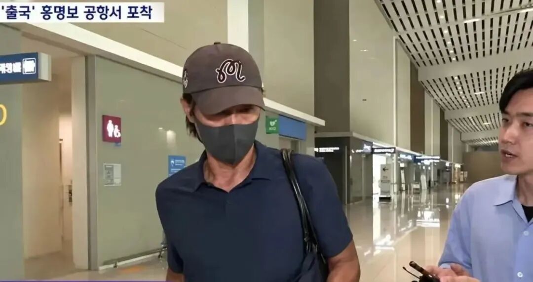在仁川国际机场,洪明甫受到韩媒记者追问。图自韩媒