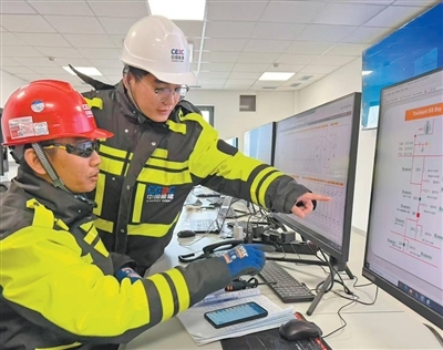 在乌兹别克斯坦塔什干光储项目储能站主控制室内，中方工程师正指导外籍员工检查线路侧运行数据。陈 鹤摄