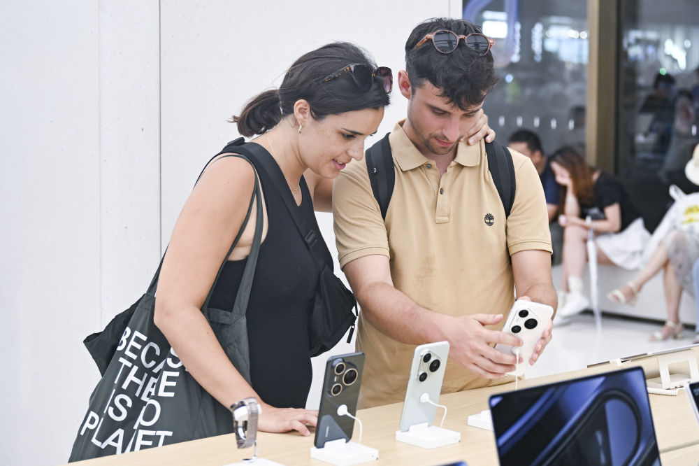 西班牙游客在上海南京路步行街的华为商店里浏览手机产品（2025年7月17日摄）。新华社记者 陈浩明 摄