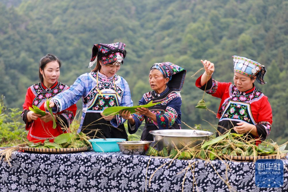 ↑ 6月17日,贵州省都匀市小围寨街道茶农村少数民族同胞在包茶香味的粽子。新华社发(肖伟摄)