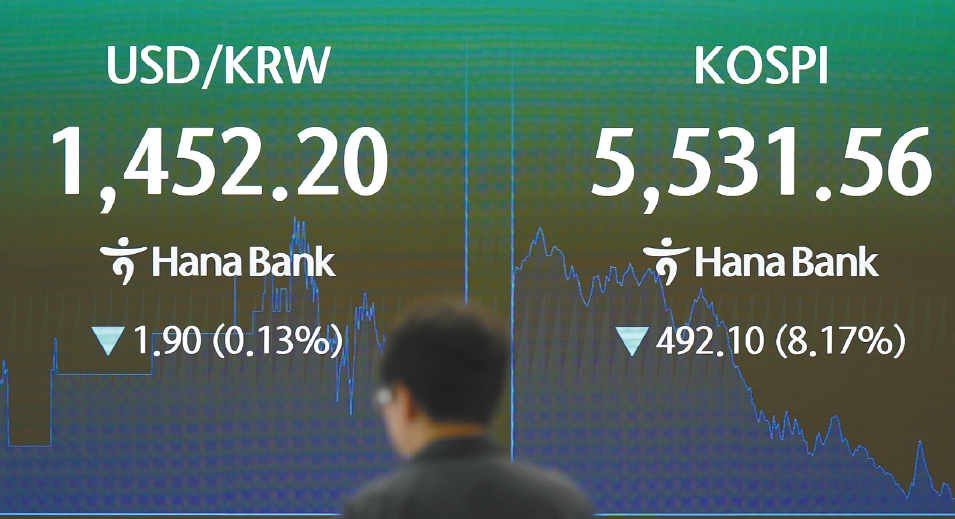 29日,韩国首尔,一名交易员走过显示韩国综合股价指数(KOSPI)及美元兑韩元汇率的屏幕。(视觉中国)