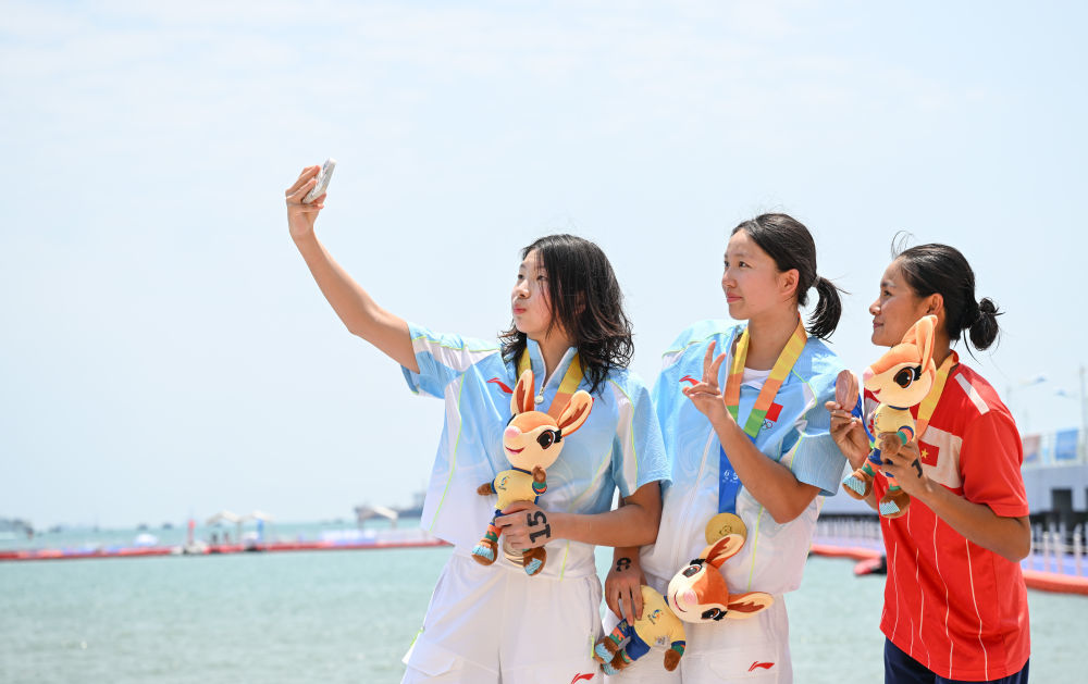 2026年4月25日,冠军中国选手李馨璇(中)、亚军中国选手陈奕静(左)和季军越南选手武美田在三亚亚沙会公开水域游泳女子5公里颁奖仪式上自拍。新华社记者 贝赫 摄