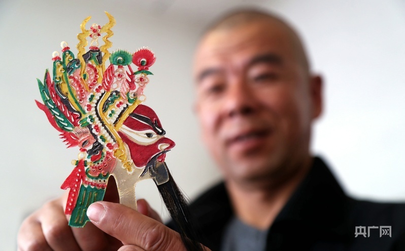 陈增光向记者展示自己制作的皮影（央广网记者 贾海元 摄）