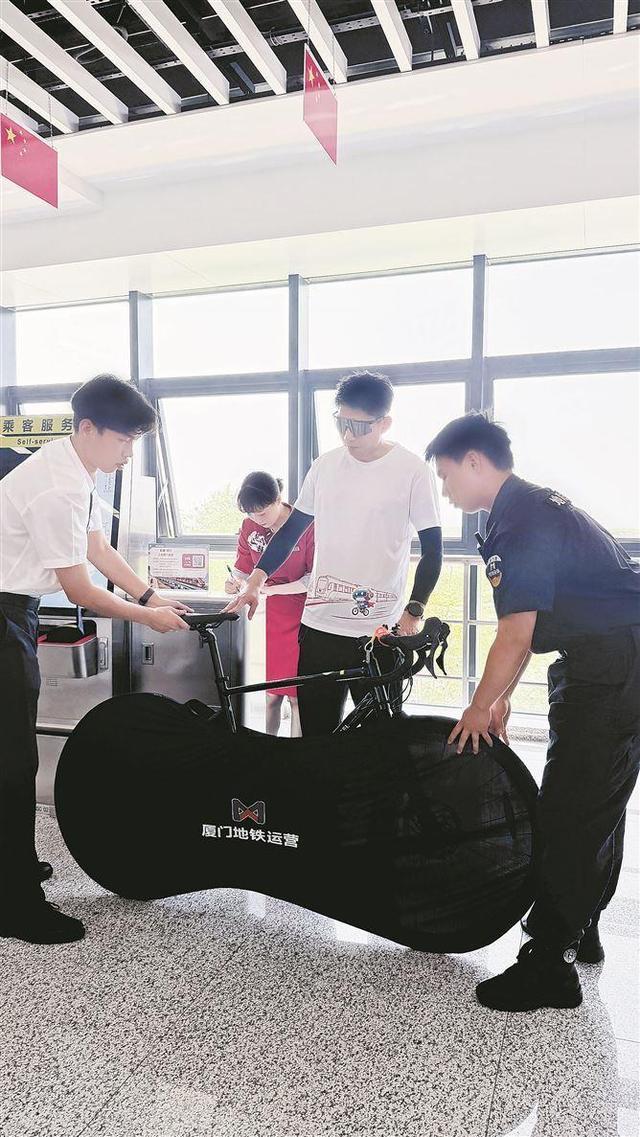 骑行爱好者陈先生在厦门地铁工作人员的帮助下,将车套上专用车袋。(厦门日报记者 谭心怡 摄)