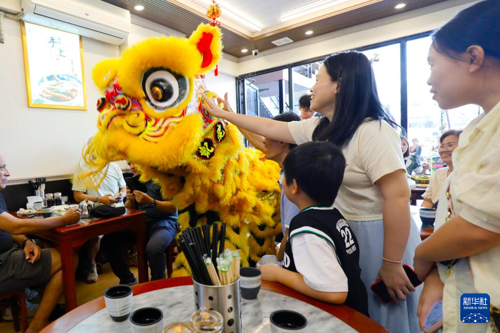 2月17日,在巴拿马首都巴拿马城,舞狮演员在一家中餐馆与顾客互动。新华社发(丹尼尔·冈萨雷斯摄)