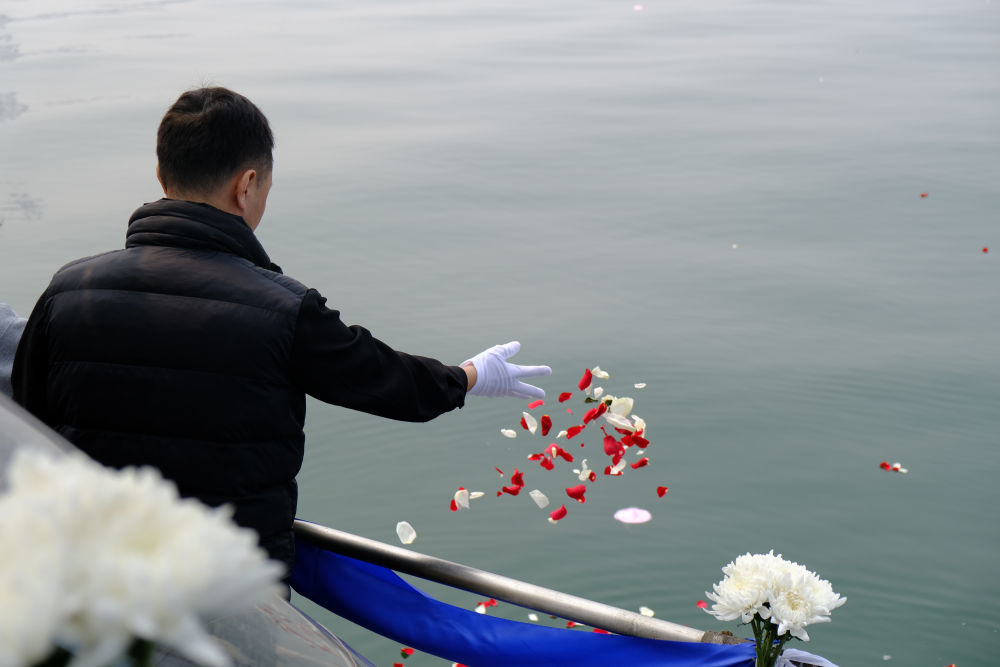 逝者家属在完成骨灰海葬仪式后将花瓣撒向大海。新华社记者 夏子麟 摄