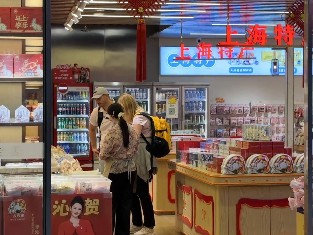 国庆假期，外国游客在上海虹桥火车站内购买上海特产。新华社发（陈晨 摄）