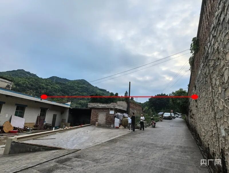 遮雨篷布横跨村道,两端分别通过房屋楼顶女儿墙与道路旁的墙体固定(央广网记者 昌思荣 摄)