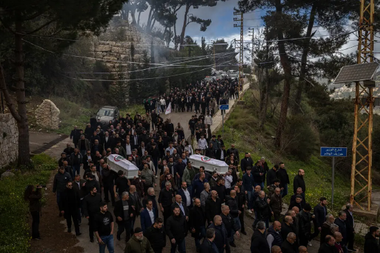 大批哀悼者聚集,部分人抬着两具覆盖着旗帜的白色棺椁