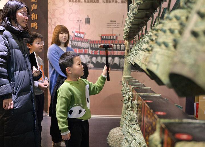 △2026年1月3日，小游客在中国考古博物馆互动展区参加仿古编钟的敲击体验活动。