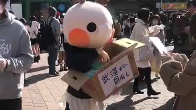 女孩在东京发爱心口罩 箱子上写着“来自武汉的报恩”