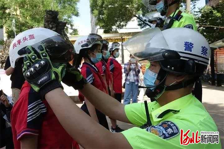 图为保定公安交警通过发放安全头盔将“一盔一带”主题安全教育活动推向深入。