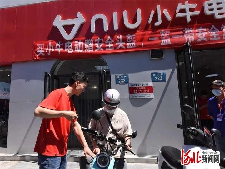 图为保定公安交警通过发放安全头盔将“一盔一带”主题安全教育活动推向深入。