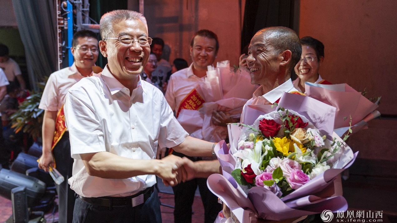 山西省政协副主席、吕梁市委书记李正印（左）与年度人物刘公平握手交谈