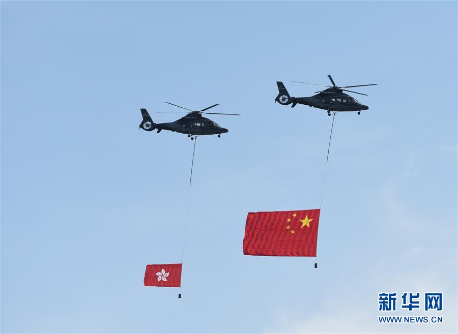 7月1日，香港特区政府在金紫荆广场举行升旗仪式，庆祝香港回归祖国20周年。这是两架分别悬挂中华人民共和国国旗、香港特区区旗的直升机从空中飞过。新华社发（王申 摄）