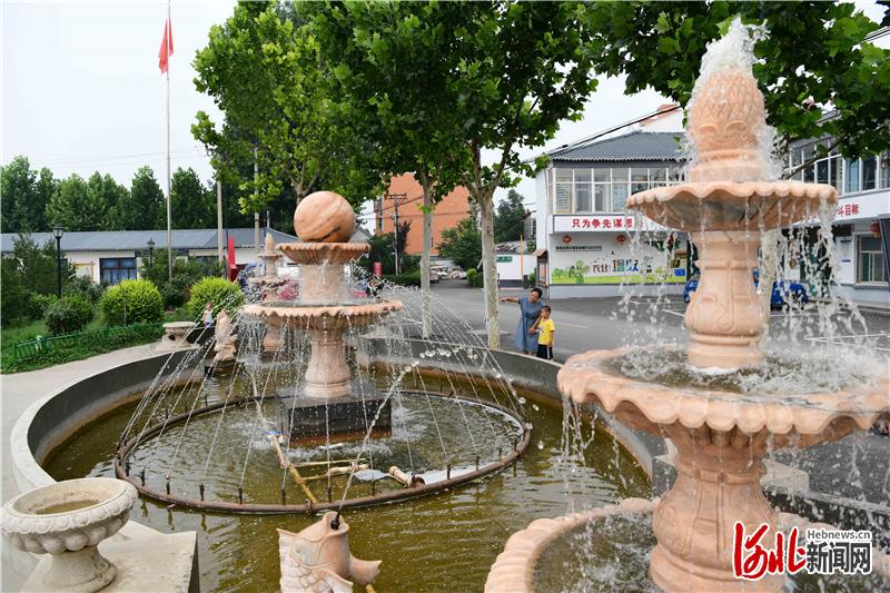 2020年7月8日，河北省邢台市南和区和阳镇巩庄村休闲广场，一名村民领着小朋友在喷泉旁玩耍。