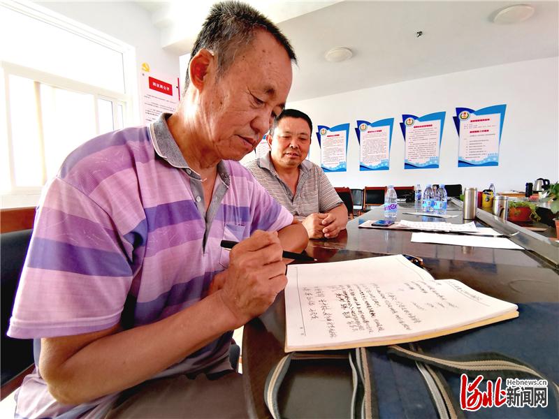 北苏闸村村委会办公室内，村委会会计苏秀山（前）正在和村委委员苏长青对账。 河北日报记者 焦磊摄