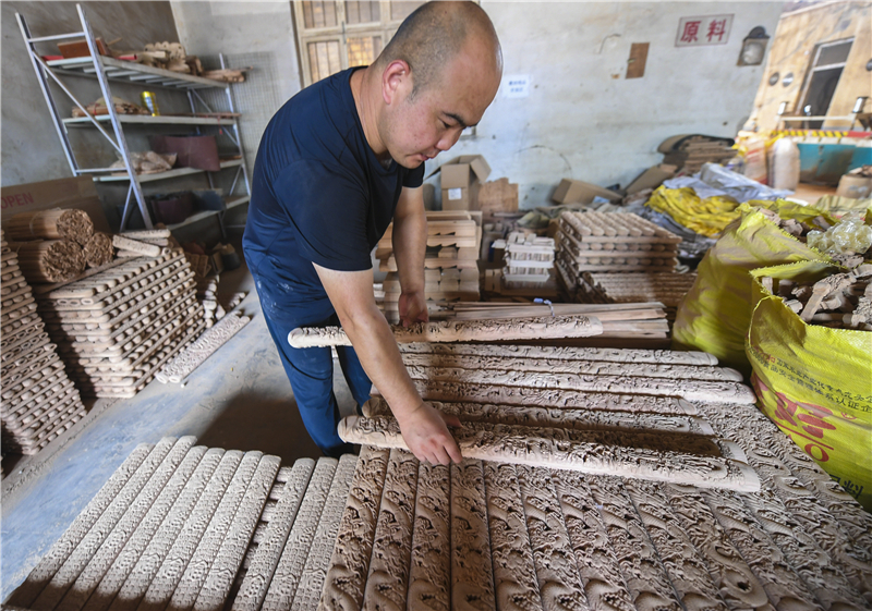 7月15日，在深州市一家文化公司，工作人员整理桃木工艺品半成品。