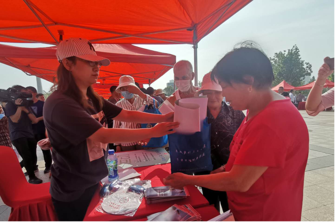 活动现场宣传区工作人员给市民发放资料并详细讲解。