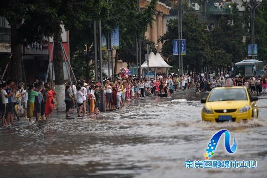 一辆出租车行驶至南滨路涉水区域，引来市民围观。