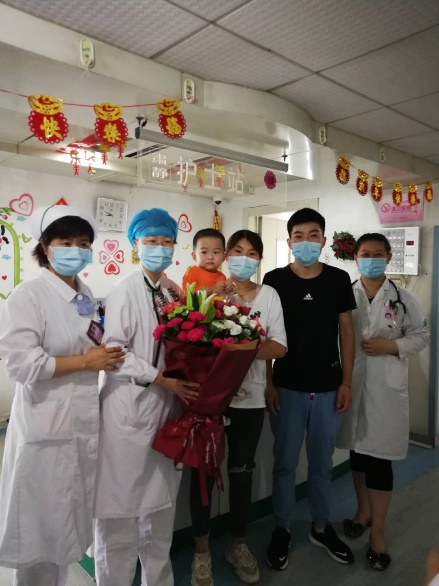 刘心洁主任与王玉珍护士长手持锦旗合影患儿及父母与医护合影