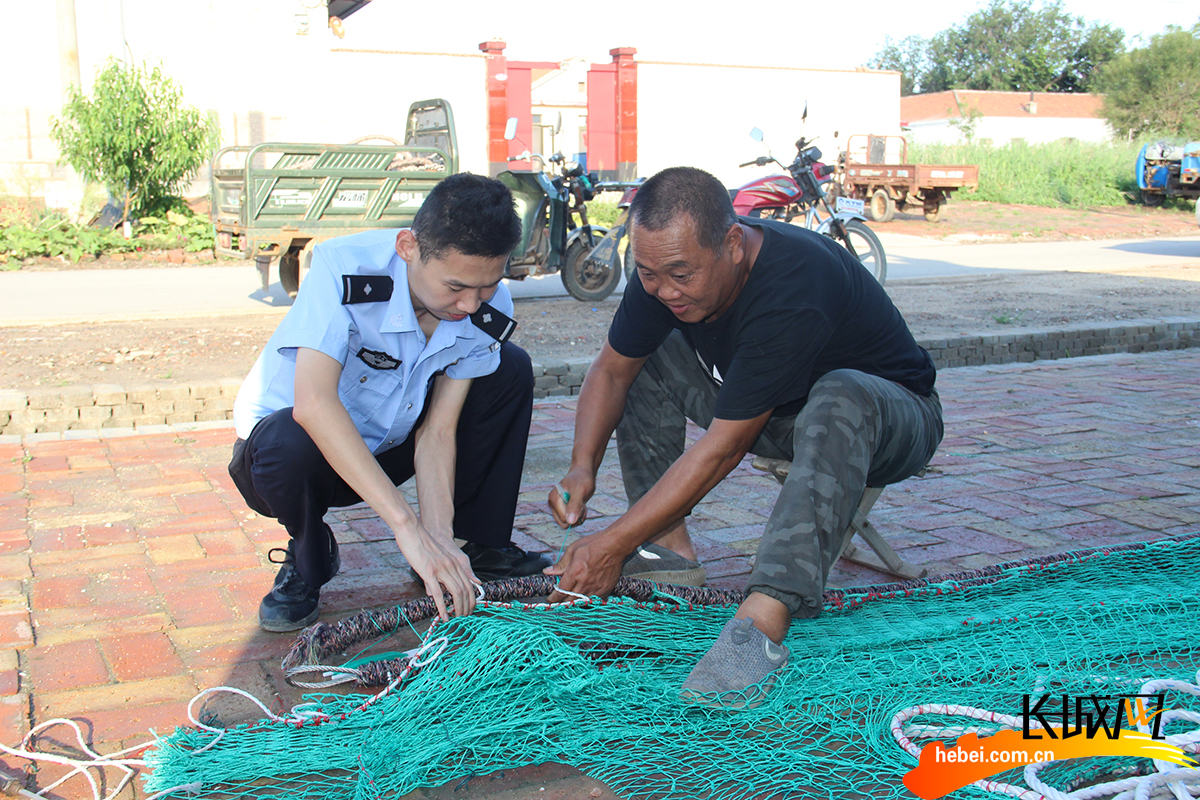 河北省公安厅海防管理总队沧州支队黄骅大队组织民警帮助渔民整理渔网。