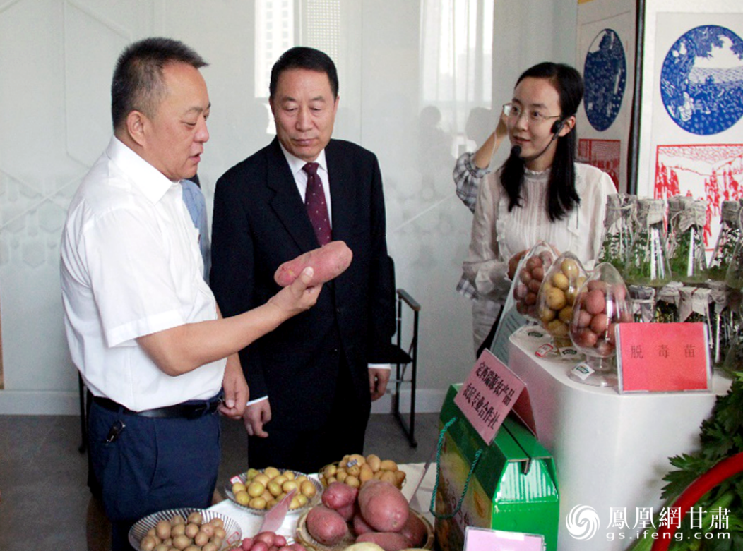 甘肃省委宣传部副部长康清（左二）出席成就展，并听取安定区委书记赵众炜（左一）介绍特色优势脱贫产业发展情况。聂颖颖 摄