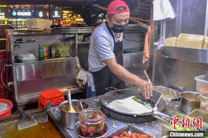 图为一名摊主给顾客摊饼。 洪坚鹏 摄