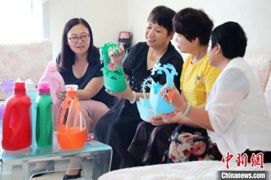 刘存芳(左二)指导邻居姐妹手工剪刻。 姚友谅 摄