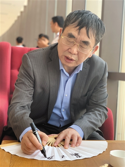 聂卫平在扇面上给棋迷签名。