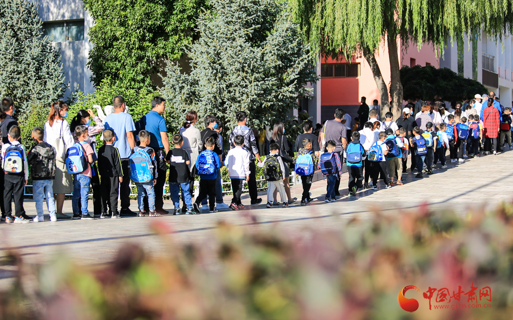 9月1日,在酒泉市西大街小学,一年级的男孩在家长的带领下参加摇号分班仪式。