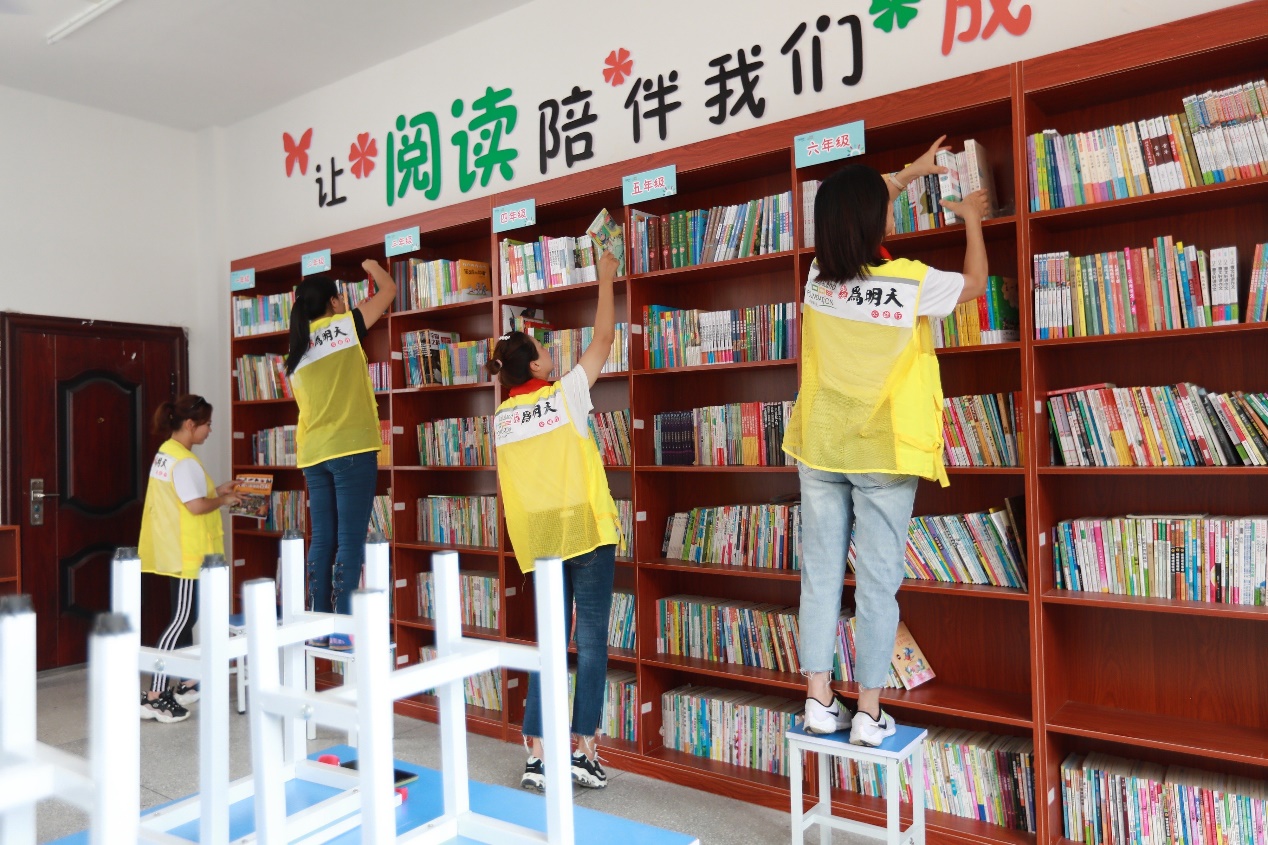 （图为：志愿者整理图书阅览室）
