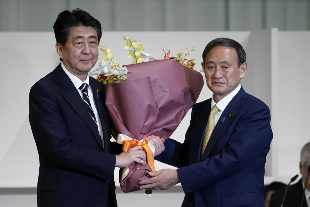 日本内阁官房长官菅义伟(右)当选自民党新总裁后向安倍晋三献花。新华社发(Pool图片,星子裕一摄)