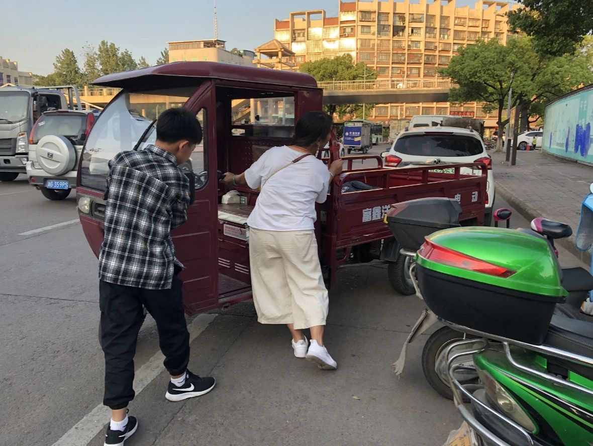 妈妈骑着电瓶车带奥华去永康西站唱歌，车里是重重的设备。新京报记者解蕾 摄
