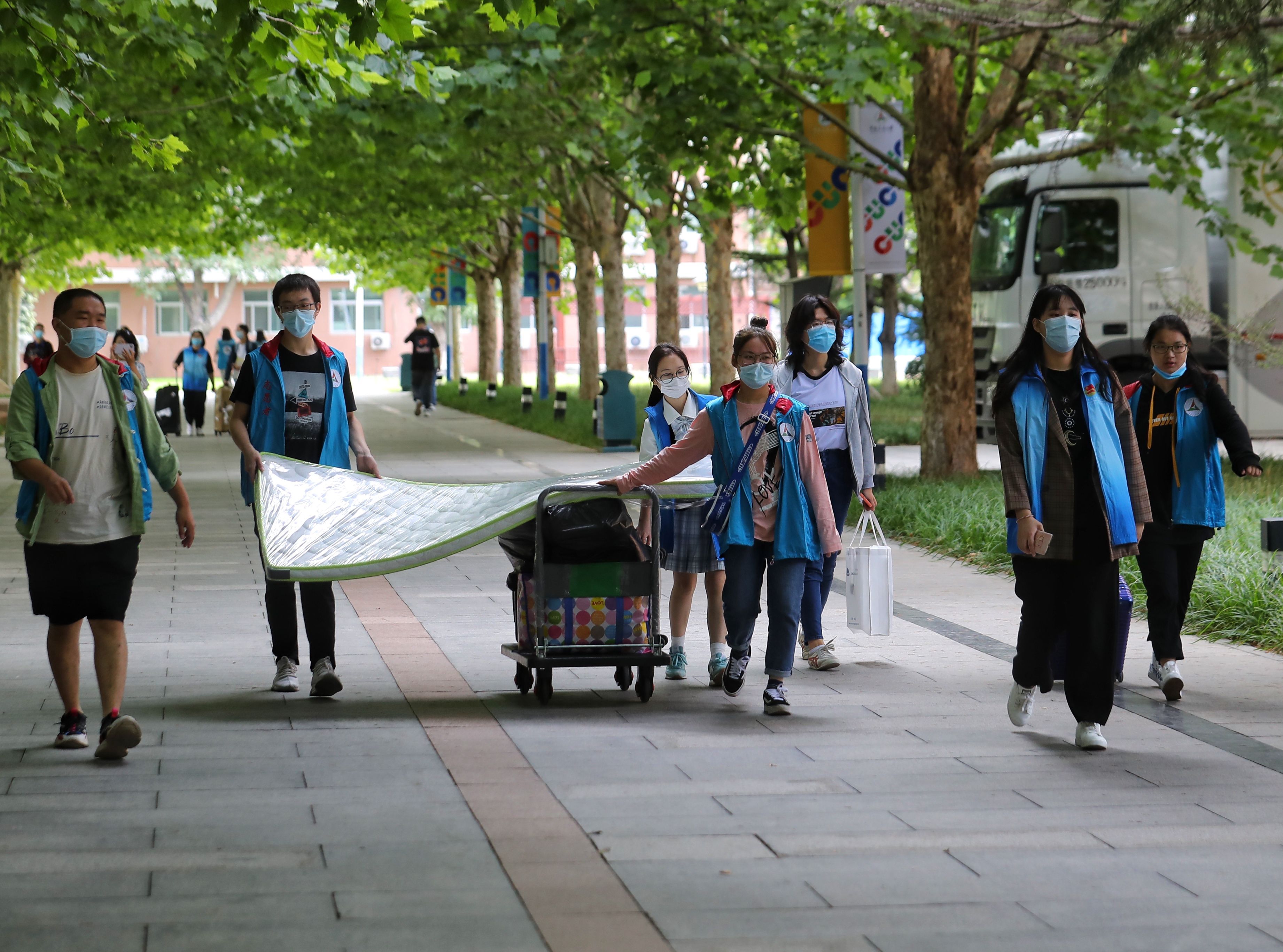 穿着蓝马甲的志愿者用小推车帮助新生运送行李和床垫。新京报记者 王贵彬 摄