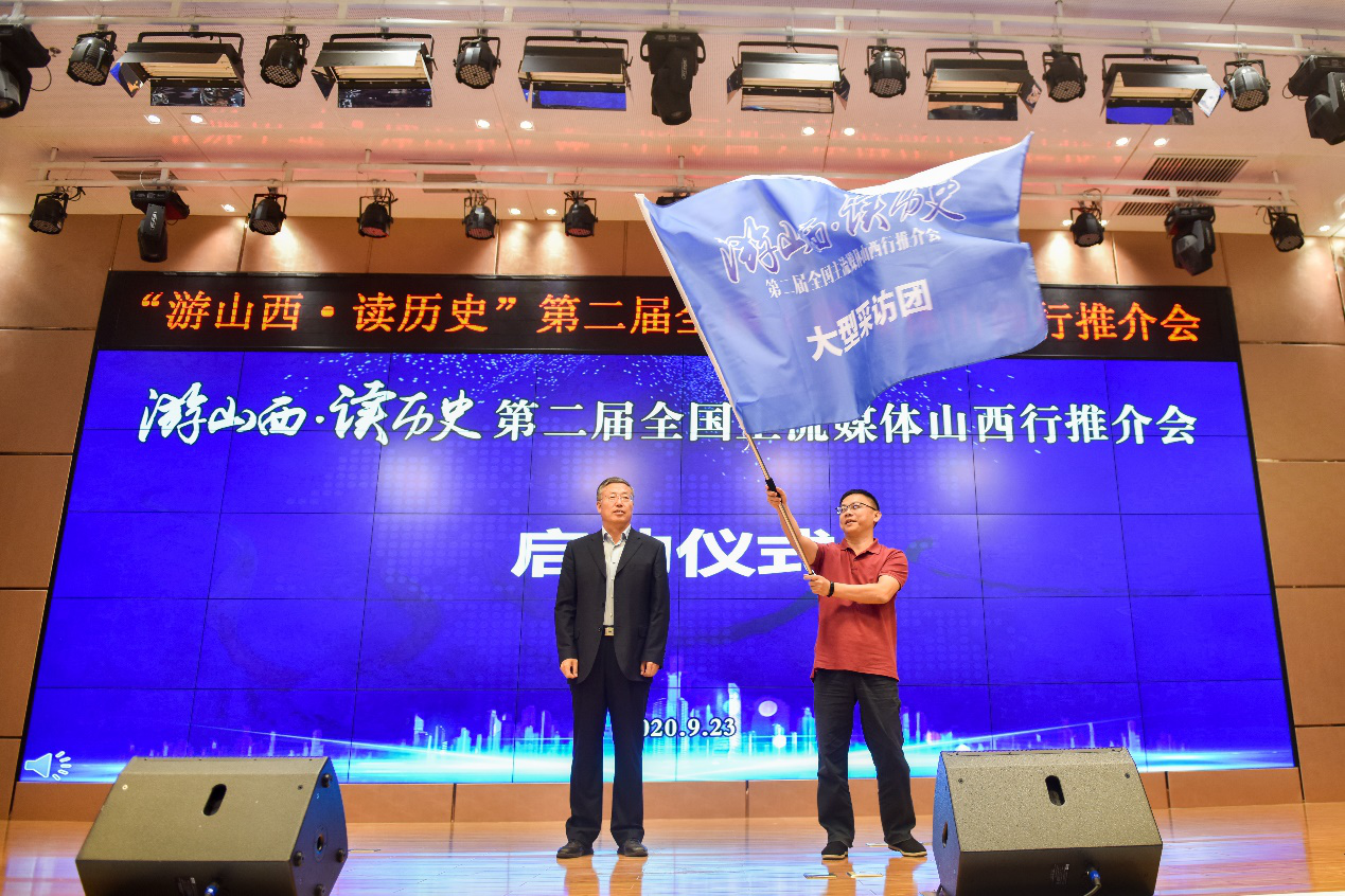 图为山西省文化和旅游厅副厅长李贵（图左）向参加此次山西行活动的媒体代表授旗（苏航 摄）