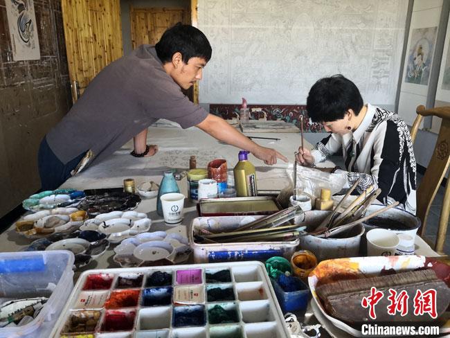 图为2020年8月下旬，敦煌“80后”画家张杰龙(左)在为云南丽江“学生”莫北讲解敦煌壁画的绘画技巧。　冯志军 摄