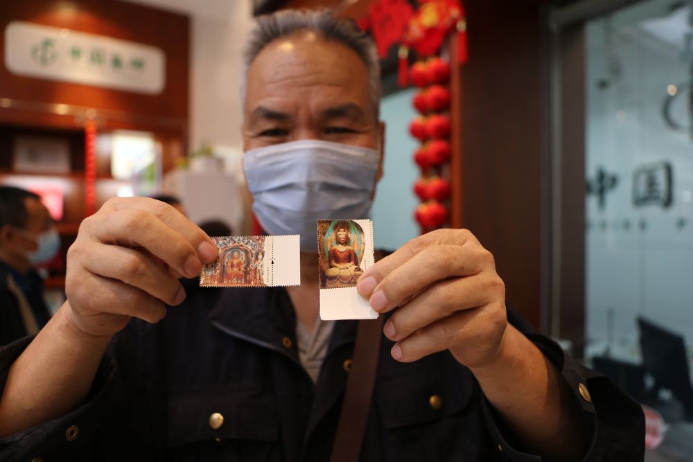 9月26日，在中国集邮专卖店兰州市平凉路店，集邮爱好者展示刚买到的《莫高窟》特种邮票。新华社记者 耿馨宁 摄