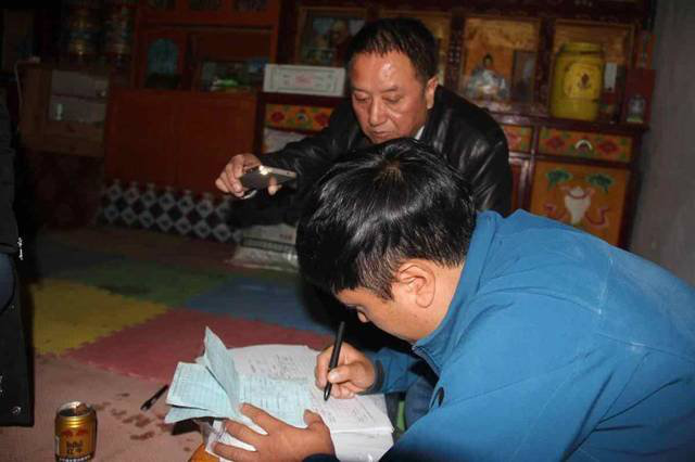 采日玛村电力不足，经常停电，村民用手电为王长山照亮。